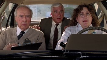 Movie still from “The Naked Gun: From the Files of Police Squad!” (1988), directed by David Zucker – A group of people in the back seat of a car; Medium shot, Over the shoulder angle