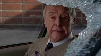 Movie still from “The Naked Gun: From the Files of Police Squad!” (1988), directed by David Zucker – An older man in a suit and tie sitting in the back of a car; Close Up shot, Over the shoulder angle
