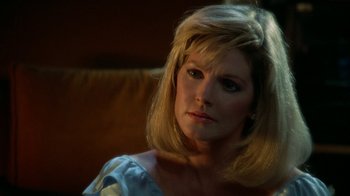 Movie still from “The Naked Gun: From the Files of Police Squad!” (1988), directed by David Zucker – A woman with blonde hair sitting on a couch; Close Up shot, Over the shoulder angle