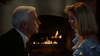Movie still from “The Naked Gun: From the Files of Police Squad!” (1988), directed by David Zucker – An older man and a younger woman in front of a fireplace; Close Up shot, Over the shoulder angle