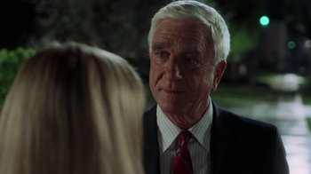 Movie still from “The Naked Gun: From the Files of Police Squad!” (1988), directed by David Zucker – An older man wearing a suit and red tie; Close Up shot, Over the shoulder angle