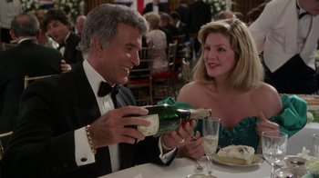 Movie still from “The Naked Gun: From the Files of Police Squad!” (1988), directed by David Zucker – A man and a woman at a table with a bottle of champagne; Medium shot, High angle