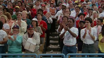 Movie still from “The Naked Gun: From the Files of Police Squad!” (1988), directed by David Zucker – A group of people standing in front of an audience clapping; Medium shot, High angle