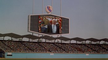 Movie still from “The Naked Gun: From the Files of Police Squad!” (1988), directed by David Zucker – A large screen in the middle of a baseball field; Extreme Wide shot, Low angle