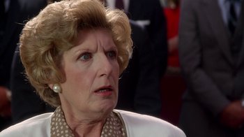 Movie still from “The Naked Gun: From the Files of Police Squad!” (1988), directed by David Zucker – An older woman with a frowning look on her face; Close Up shot, Over the shoulder angle