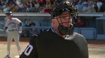 Movie still from “The Naked Gun: From the Files of Police Squad!” (1988), directed by David Zucker – A man wearing a catchers mask in front of a crowd of people; Medium shot, Over the shoulder angle