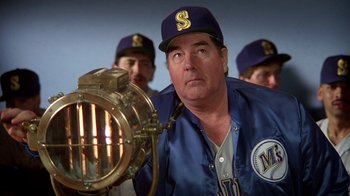 Movie still from “The Naked Gun: From the Files of Police Squad!” (1988), directed by David Zucker – A man in a baseball uniform looking at a camera; Medium shot, Low angle