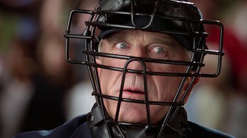 Movie still from “The Naked Gun: From the Files of Police Squad!” (1988), directed by David Zucker – An older man wearing a baseball catcher's mask; Close Up shot, Over the shoulder angle