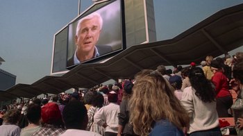 Movie still from “The Naked Gun: From the Files of Police Squad!” (1988), directed by David Zucker – A crowd of people standing around watching a television screen; Medium shot, Low angle