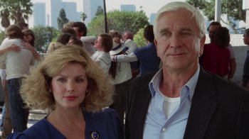 Movie still from “The Naked Gun: From the Files of Police Squad!” (1988), directed by David Zucker – A man and a woman standing next to each other; Medium shot, Low angle