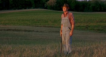 Movie still from “The Natural” (1984), directed by Barry Levinson – A man in overalls standing in a field holding a rifle; Wide shot, Low angle