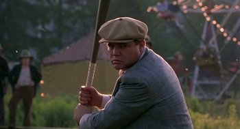 Movie still from “The Natural” (1984), directed by Barry Levinson – A man holding a baseball bat while wearing a hat; Medium shot, Low angle