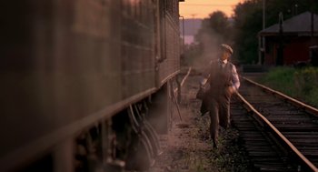 Movie still from “The Natural” (1984), directed by Barry Levinson – A man walking on a train track next to a train car; Wide shot, High angle