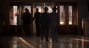 Movie still from “The Natural” (1984), directed by Barry Levinson – A group of men in suits and hats walking through a building; Wide shot, Low angle