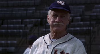 Movie still from “The Natural” (1984), directed by Barry Levinson – An older man in a baseball uniform with a hat on; Close Up shot, Low angle
