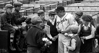 Movie still from “The Natural” (1984), directed by Barry Levinson – A group of young men standing next to each other on top of a baseball field; Medium shot, Over the shoulder angle