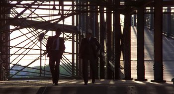 Movie still from “The Natural” (1984), directed by Barry Levinson – Two men in suits and hats are walking on a bridge; Wide shot, Low angle