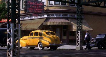 Movie still from “The Natural” (1984), directed by Barry Levinson – An old car parked on the side of the street; Wide shot, Low angle