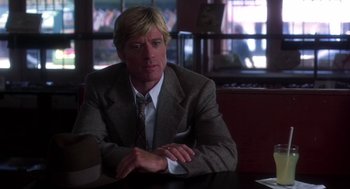 Movie still from “The Natural” (1984), directed by Barry Levinson – A man sitting at a table in front of a window; Close Up shot, Over the shoulder angle