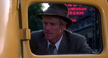 Movie still from “The Natural” (1984), directed by Barry Levinson – A man wearing a suit and a hat looking out of a car window; Close Up shot, Over the shoulder angle