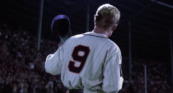 Movie still from “The Natural” (1984), directed by Barry Levinson – A baseball player holding a bat on top of a baseball field; Medium shot, Low angle