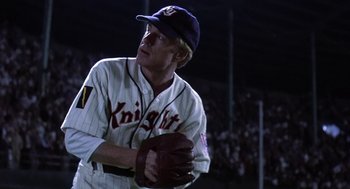 Movie still from “The Natural” (1984), directed by Barry Levinson – A man in a baseball uniform holding a ball in his hand; Medium shot, Low angle