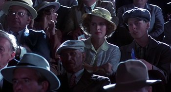 Movie still from “The Natural” (1984), directed by Barry Levinson – A woman wearing a hat in a crowd of people; Medium shot, Over the shoulder angle