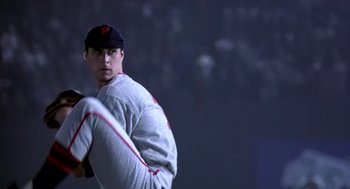 Movie still from “The Natural” (1984), directed by Barry Levinson – A baseball player is holding a baseball bat in his hand; Medium shot, Low angle