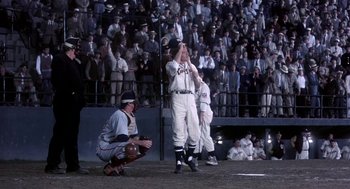 Movie still from “The Natural” (1984), directed by Barry Levinson – A baseball player is standing in front of a crowd of people; Wide shot, High angle