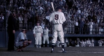 Movie still from “The Natural” (1984), directed by Barry Levinson – A baseball player holding a baseball bat on top of a baseball field; Wide shot, Low angle