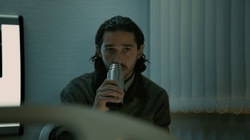 Movie still from “Charlie Countryman” (2013), directed by Fredrik Bond – A man sitting in front of a window holding a drink; Close Up shot, Over the shoulder angle