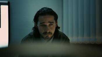 Movie still from “Charlie Countryman” (2013), directed by Fredrik Bond – A man with long black hair looking at a computer screen; Close Up shot, Low angle
