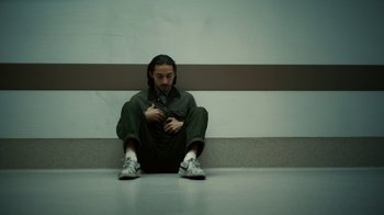 Movie still from “Charlie Countryman” (2013), directed by Fredrik Bond – A man sitting on the ground looking at his cell phone; Medium shot, Low angle