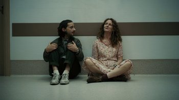 Movie still from “Charlie Countryman” (2013), directed by Fredrik Bond – A man and a woman sitting next to each other on the ground; Medium shot, Low angle