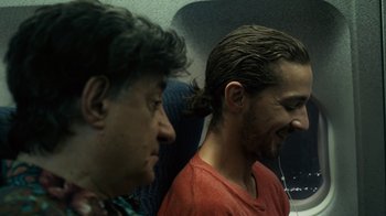 Movie still from “Charlie Countryman” (2013), directed by Fredrik Bond – A man with long hair is sitting next to another man with long hair; Close Up shot, Over the shoulder angle