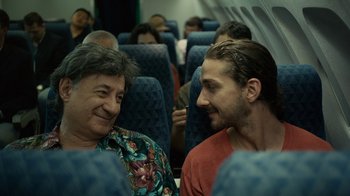 Movie still from “Charlie Countryman” (2013), directed by Fredrik Bond – Two men are sitting on a plane and talking; Close Up shot, Over the shoulder angle
