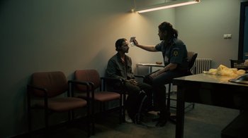 Movie still from “Charlie Countryman” (2013), directed by Fredrik Bond – Two men sitting in a waiting room talking to a police officer; Medium shot, Over the shoulder angle
