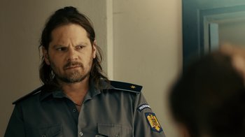 Movie still from “Charlie Countryman” (2013), directed by Fredrik Bond – A man with long hair wearing a police uniform; Close Up shot, Over the shoulder angle