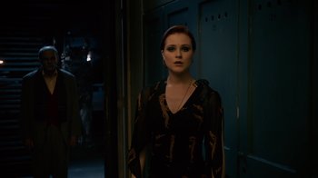 Movie still from “Charlie Countryman” (2013), directed by Fredrik Bond – A woman standing in a dark room wearing a black dress; Medium shot, Over the shoulder angle