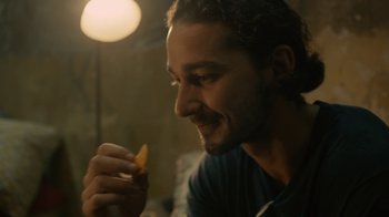 Movie still from “Charlie Countryman” (2013), directed by Fredrik Bond – A person holding a piece of food; Close Up shot, Over the shoulder angle