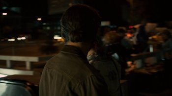 Movie still from “Charlie Countryman” (2013), directed by Fredrik Bond – A man with a bun is standing in the dark; Close Up shot, Over the shoulder angle