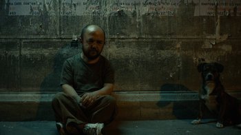 Movie still from “Charlie Countryman” (2013), directed by Fredrik Bond – A man sitting on the ground in front of a wall; Wide shot, High angle