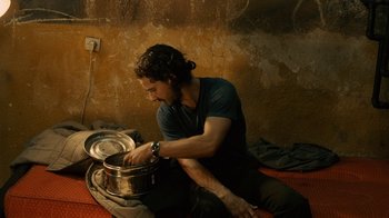 Movie still from “Charlie Countryman” (2013), directed by Fredrik Bond – A man sitting on the floor with a pan in his hand; Medium shot, High angle