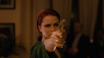 Movie still from “Charlie Countryman” (2013), directed by Fredrik Bond – A woman with red hair is holding a gun; Close Up shot, Over the shoulder angle
