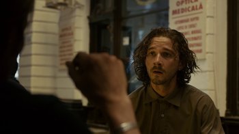 Movie still from “Charlie Countryman” (2013), directed by Fredrik Bond – A man with long brown hair is looking into the mirror; Close Up shot, Over the shoulder angle