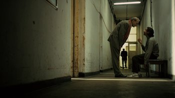 Movie still from “Charlie Countryman” (2013), directed by Fredrik Bond – A man leaning against a wall in a building; Wide shot, Low angle
