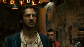 Movie still from “Charlie Countryman” (2013), directed by Fredrik Bond – A man standing next to another man in a hallway; Close Up shot, Low angle