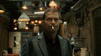 Movie still from “Charlie Countryman” (2013), directed by Fredrik Bond – A person wearing a suit smoking a cigarette; Medium shot, Low angle