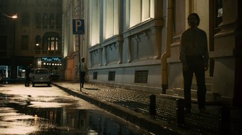 Movie still from “Charlie Countryman” (2013), directed by Fredrik Bond – A person walking down the street in the rain; Extreme Wide shot, Low angle