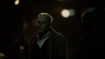Movie still from “Charlie Countryman” (2013), directed by Fredrik Bond – An older man wearing a sweater and a scarf; Close Up shot, Low angle